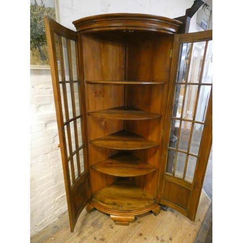 204 - A Georgian style pale mahogany bow fronted corner cabinet with bevelled glass door panels