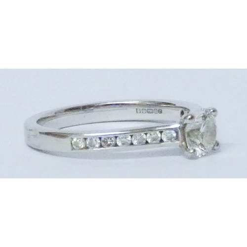 682 - Modern 18ct white gold diamond engagement ring, set with a claw set brilliant cut diamond with chann... 