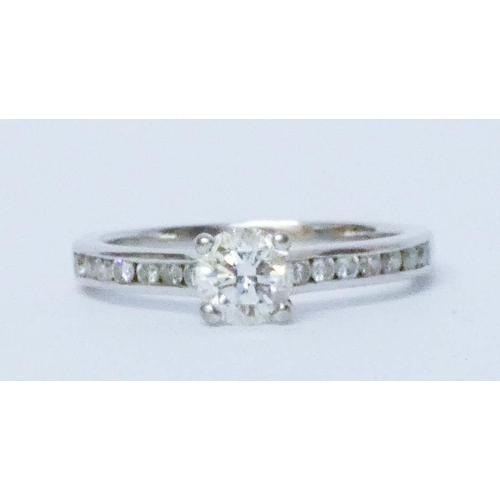 682 - Modern 18ct white gold diamond engagement ring, set with a claw set brilliant cut diamond with chann... 