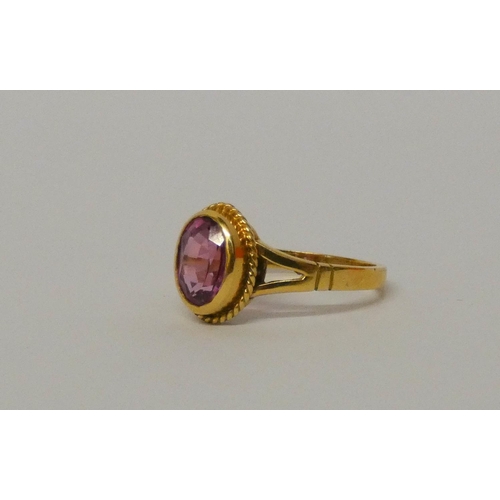 571 - 18ct yellow gold single stone pink sapphire ring, in oval rub over setting. Hallmarked ring size P