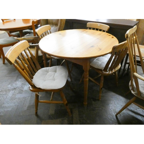 34 - A circular pine extending dining table and four similar Windsor spindle back dining chairs...