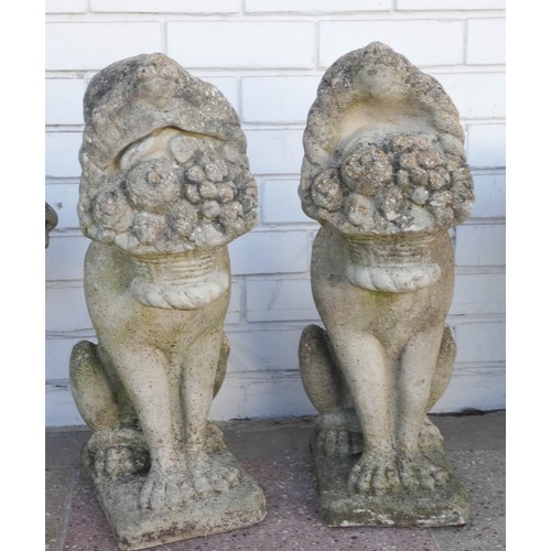 502 - A pair of reconstituted stone garden ornaments modelled as dogs holding baskets in their mouths