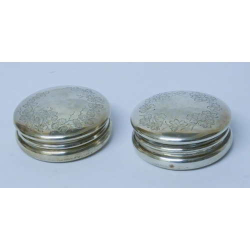 594 - A pair of silver circular pill boxes, with engraved floral decoration and gilded interiors, London 1... 