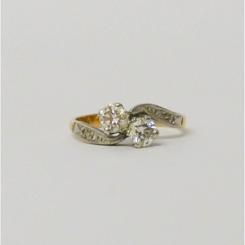 706 - A vintage two stone diamond ring, in a cross over design with diamond shoulders, shank marked '18ct'... 