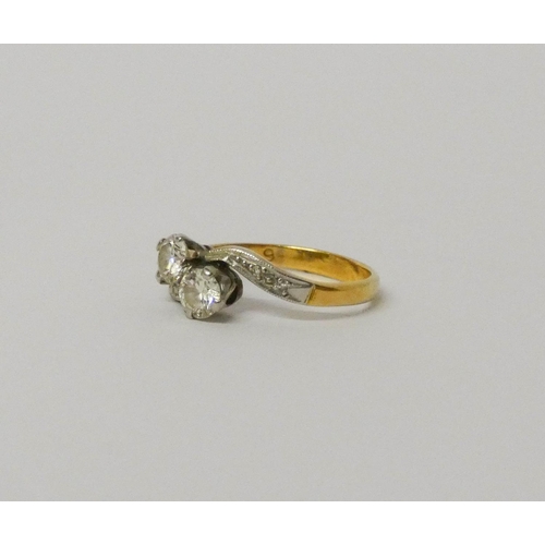 706 - A vintage two stone diamond ring, in a cross over design with diamond shoulders, shank marked '18ct'... 