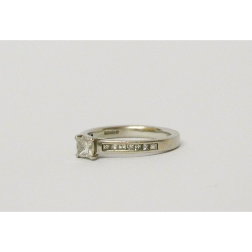 721 - A diamond engagement ring, set with a princess cut diamonds on diamond shoulders on platinum band, h... 