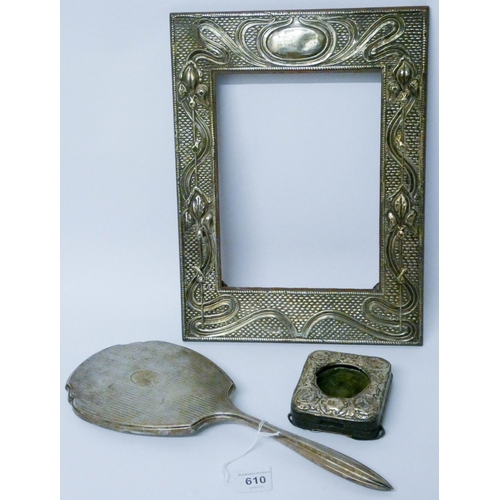 610 - A large Art Nouveau silver photograph frame, a smaller silver embossed travel watch holder and a sil...