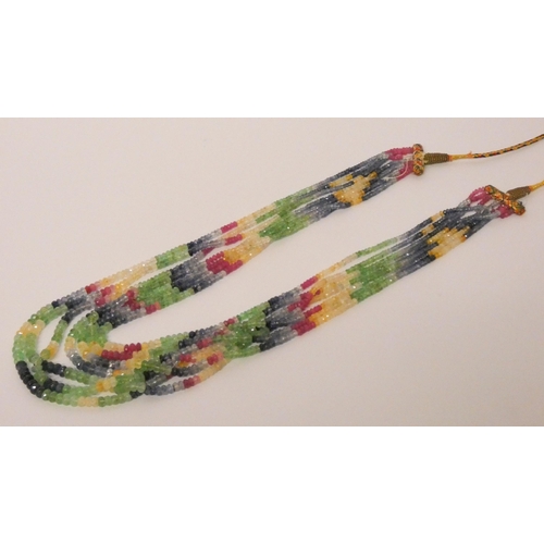 708 - An Indian seven strand precious stone bead necklace, of sapphires, rubies, emeralds. On a woven coll... 