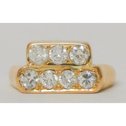 745 - A seven stone diamond ring, the brilliant cut diamonds in a rub over rectangular panel, unmarked yel... 