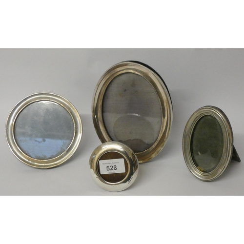 528 - A collection of four hallmarked silver oval and circular silver easel photograph frames