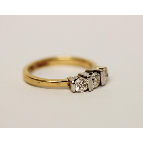 615 - A three stone diamond ring, on 18ct yellow band. Marked 750 Gross weight 3.7g, ring size L