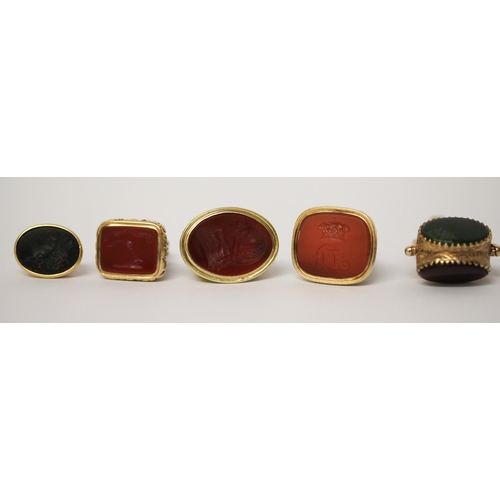 638 - A large triple stone set swivel fob and four 19th century carved intaglio panel fobs, all set in unm... 