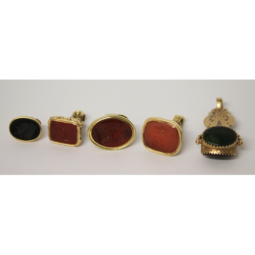 638 - A large triple stone set swivel fob and four 19th century carved intaglio panel fobs, all set in unm... 