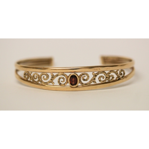 671 - 9ct yellow gold open work bangle set with oval garnet to the centre, hallmarked, 6.1gms