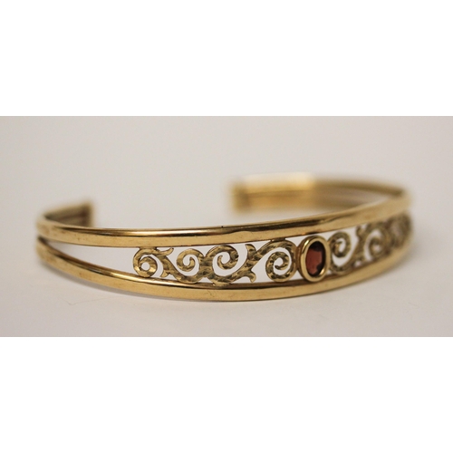 671 - 9ct yellow gold open work bangle set with oval garnet to the centre, hallmarked, 6.1gms