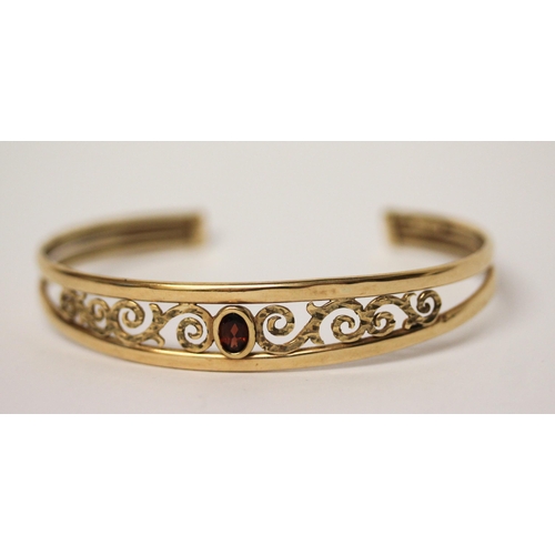 671 - 9ct yellow gold open work bangle set with oval garnet to the centre, hallmarked, 6.1gms