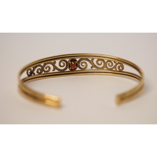 671 - 9ct yellow gold open work bangle set with oval garnet to the centre, hallmarked, 6.1gms