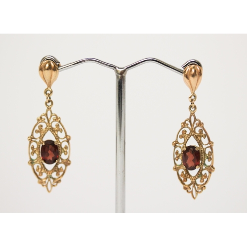 673 - A pair of 9ct gold garnet filigree drop earrings