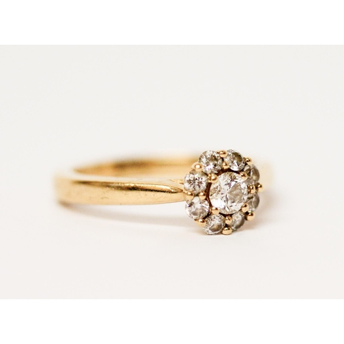 679 - A diamond cluster ring on an 18ct yellow gold shank, hallmarked, diamond weight 51 pts marked in sha... 