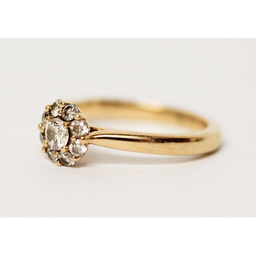 679 - A diamond cluster ring on an 18ct yellow gold shank, hallmarked, diamond weight 51 pts marked in sha... 