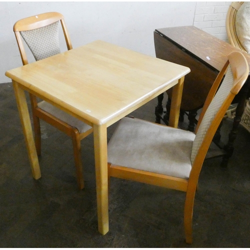 251 - A small square light beech kitchen table and two chairs with upholstered seats and backs