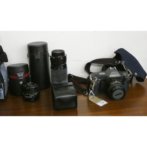 124 - A Cannon T70 camera with three various lenses, carrying bag etc