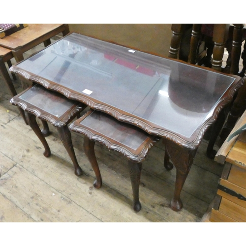 133 - A long reproduction mahogany coffee table with glass top and two smaller ones under