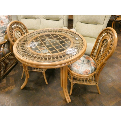 233 - A circular bamboo conservatory table with glass top and a pair of matching chairs with upholstered s... 