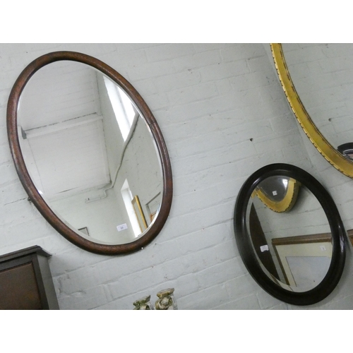 50 - A large oval bevelled mirror in oak frame and a smaller mahogany framed oval mirror