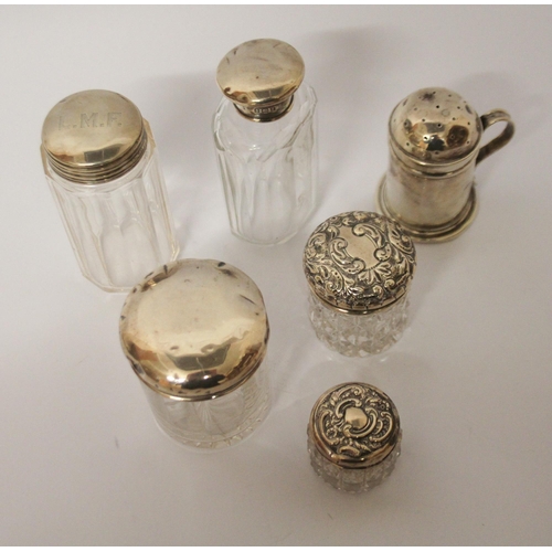 550 - A silver pepperette and a collection of silver topped dressing table jars.