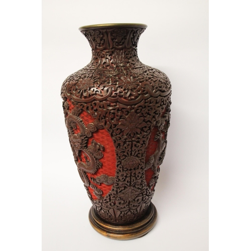 313 - A large cinnabar lacquer and blue enamel highly carved Chinese vase on a hardwood stand, 16