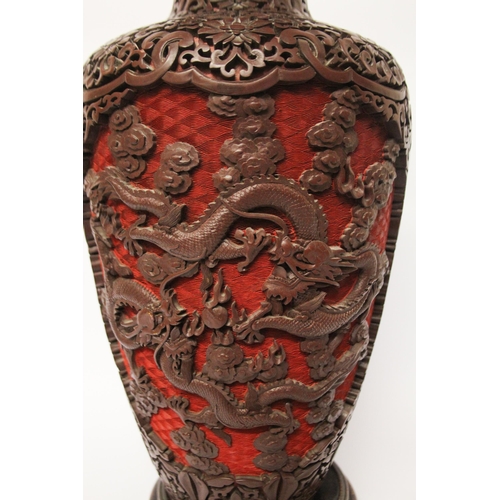 313 - A large cinnabar lacquer and blue enamel highly carved Chinese vase on a hardwood stand, 16