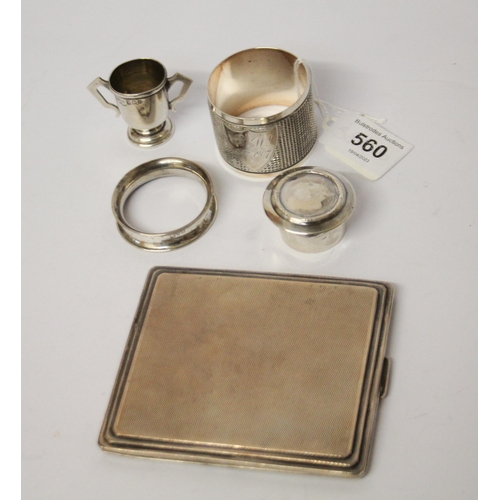 560 - An engine turned silver cigarette case, napkin rings and small silver trophy cup etc. 6 troy ounces