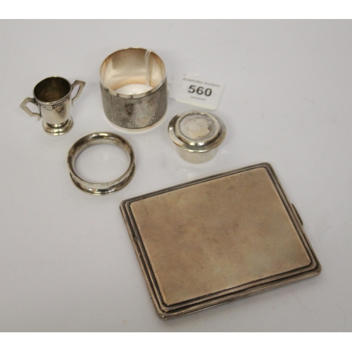 560 - An engine turned silver cigarette case, napkin rings and small silver trophy cup etc. 6 troy ounces