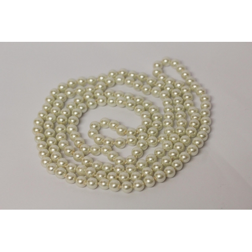 596 - A long row of uniform cultured pearls, individually knotted rope, 140 cms long approx