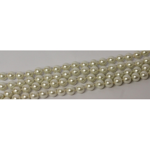 596 - A long row of uniform cultured pearls, individually knotted rope, 140 cms long approx