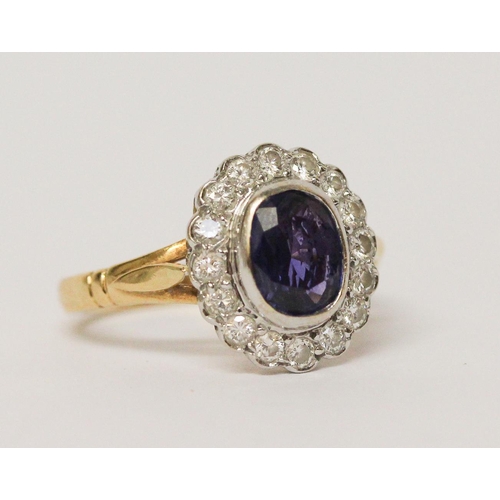 649 - A modern sapphire and diamond oval cluster ring, oval sapphire of good colour in rub over setting su... 