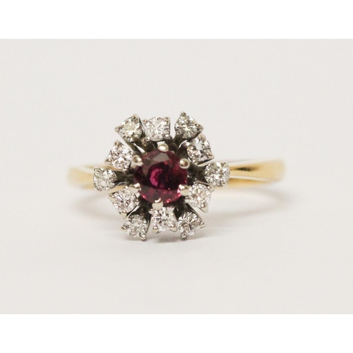 651 - A ruby and diamond cluster ring, in a circular design, on yellow 18ct gold band. Marked '18ct'. Ring... 