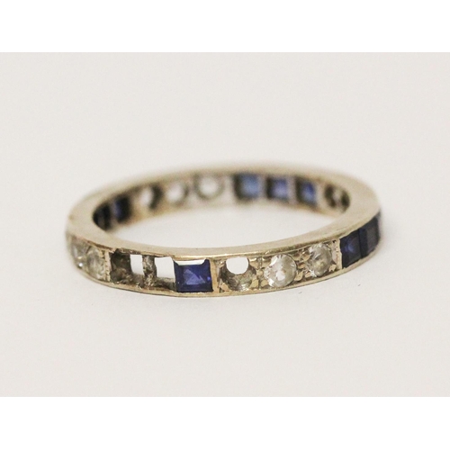 654 - A sapphire and white stone full eternity ring, unmarked white metal. Ring size M