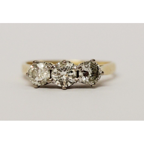 724 - A three stone diamond ring, in claw setting on 18ct hallmarked yellow gold band, total diamond weigh... 