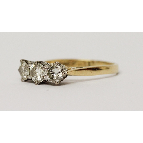 724 - A three stone diamond ring, in claw setting on 18ct hallmarked yellow gold band, total diamond weigh... 