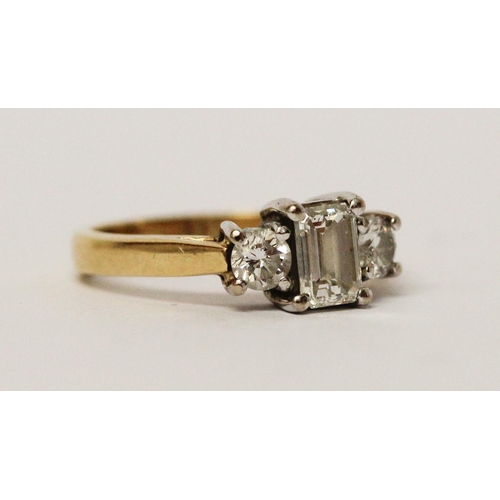 734 - A three stone diamond ring, with central emerald cut diamond flanked by princess cut diamonds, on 18... 