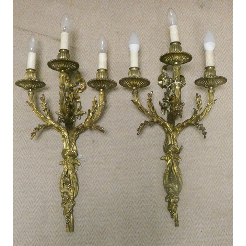 302 - A pair of early 20th century gilt brass three branch wall sconces, wired for electricity, overall le... 