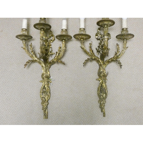 302 - A pair of early 20th century gilt brass three branch wall sconces, wired for electricity, overall le... 