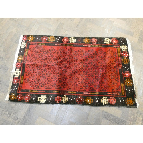 173 - A red and black patterned Afghan wool pile rug, 4'5 x 2'10