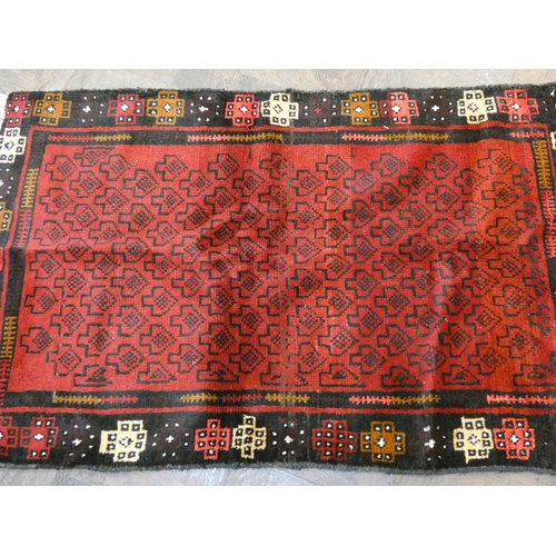 173 - A red and black patterned Afghan wool pile rug, 4'5 x 2'10