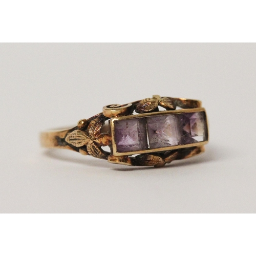 538 - A three stone amethyst ring, in carved 14ct yellow gold setting, shank marked 585. Ring size P