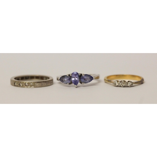 564 - A vintage three stone diamond ring, an eternity ring and a silver dress ring set with blue stones.