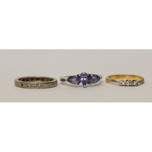 564 - A vintage three stone diamond ring, an eternity ring and a silver dress ring set with blue stones.