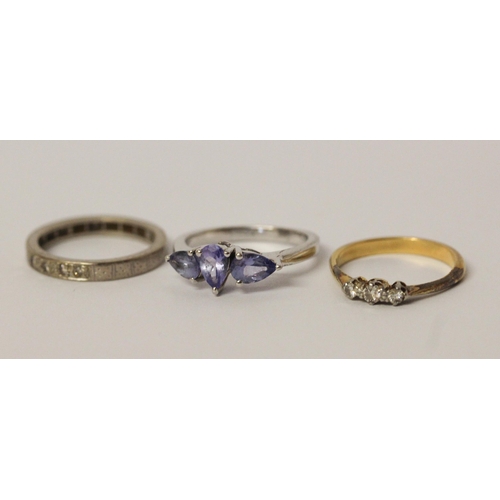 564 - A vintage three stone diamond ring, an eternity ring and a silver dress ring set with blue stones.